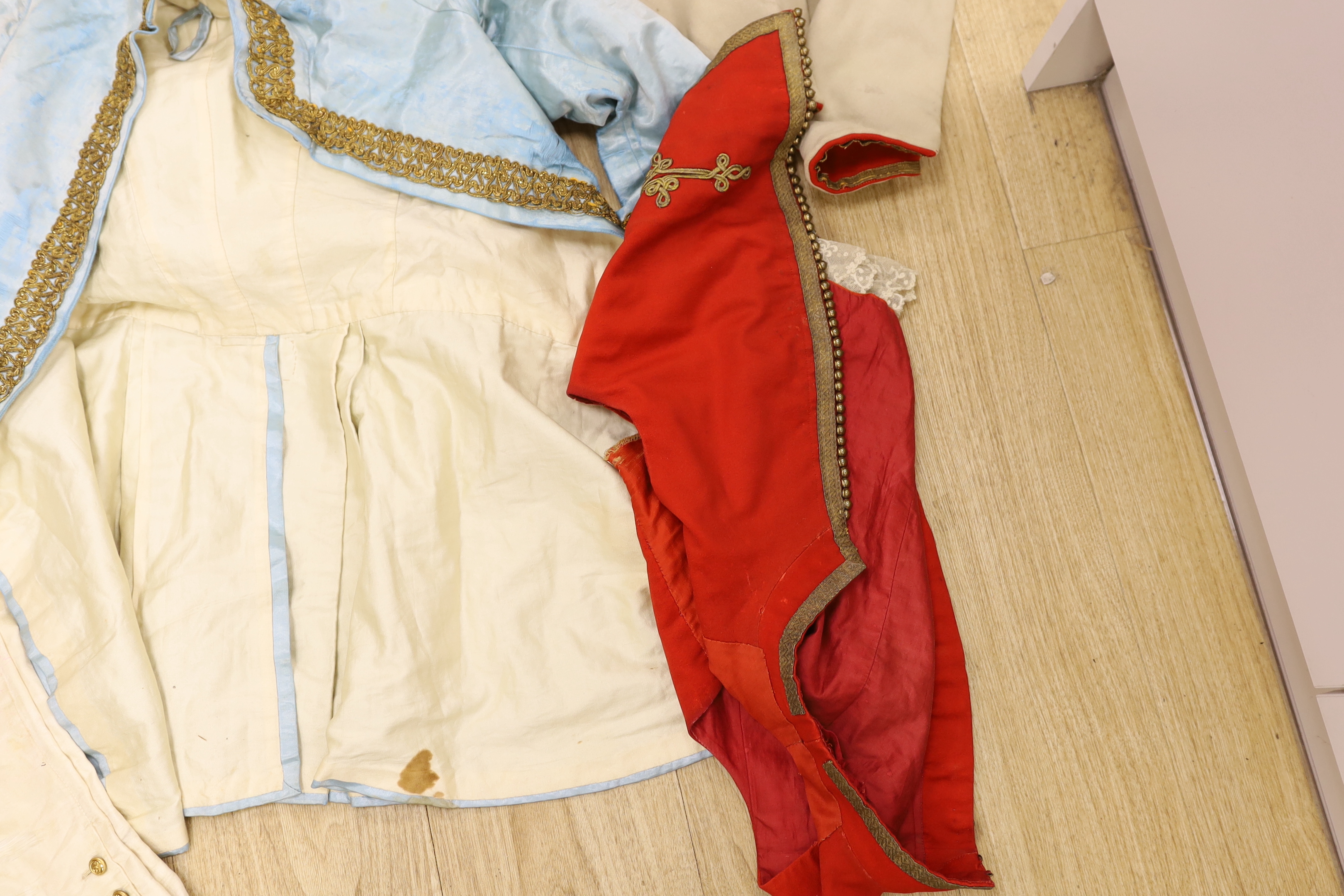 A red wool and gold braided gentleman's jacket with waistcoat, possibly originally military with later alterations, a similar blue satin jacket, etc.